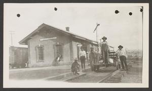 Primary view of object titled '[Men standing on train tracks next to a building]'.