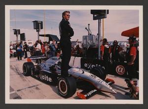 Primary view of object titled '[Eddie Cheever standing on the wheel of his car]'.