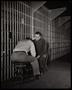 Photograph: [Two seated men talking in a prison]