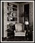 Photograph: [A chair, lamp, books and collectibles in a space]