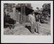 Photograph: [A couple outside of a wooden home]