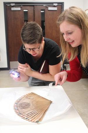 Primary view of object titled '[SMU graduate student and TCU faculty member examines an eighteenth-century fan, 2]'.