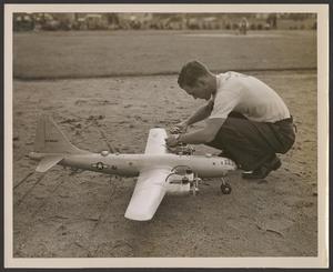 Primary view of object titled '[Technician preparing a Forster-powered model airplane outdoors]'.