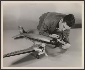 Primary view of object titled '[A technician readying a model of a DC-3 airliner]'.