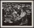 Photograph: [Women in a factory sitting at desks and sewing]