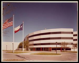 Primary view of object titled '[Exterior of an office building with an American flag and Texas flag]'.