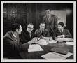 Photograph: [A group of men in suits at a table with books]