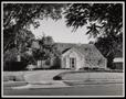 Photograph: [Exterior of a house with a plant-lined driveway]