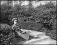 Photograph: [Woman sitting on the stairs next to hedges, 2]