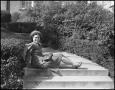 Photograph: [Woman sitting on the stairs next to hedges]