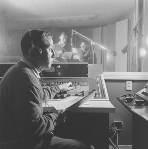 Primary view of object titled '[A man holding paper beside recording equipment, 1]'.