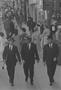 Photograph: [Three men walking down a crowded sidewalk]