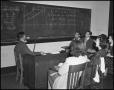 Photograph: [Students and Professor Sitting Around a Blackboard]