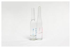 Dos ampollas largas transparentes están una al lado de la otra. La de la izquierda tiene marcas azules y la de la derecha tiene marcas rosas.