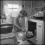 Photograph: [A woman pulling food from an oven]