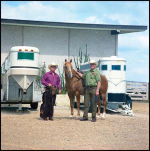 Primary view of object titled '[Rex Cauble in front of horse trailers (full view)]'.