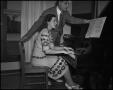 Photograph: [Woman playing the piano with her instructor]