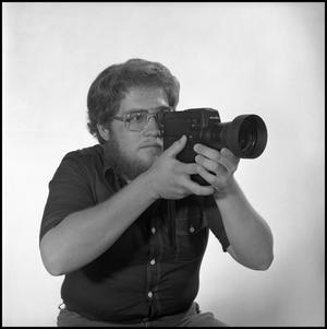 Primary view of object titled '[Lewis Abernathy posing with film camera]'.