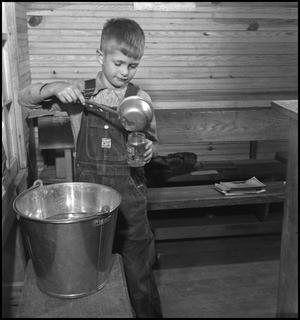Primary view of object titled '[Boy fills his drinking glass]'.