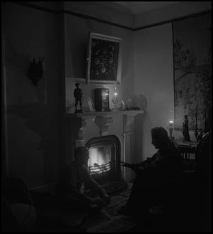 Primary view of object titled '[Sitting by fireplace]'.