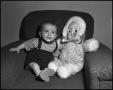 Photograph: [Baby sitting next to a doll in a sofa chair]