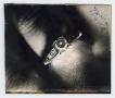 Photograph: [Folded photograph of a ring on a finger]