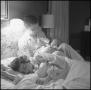 Photograph: [Photograph of a man bottle feeding his baby in bed, 1]
