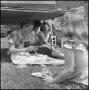 Photograph: [Photograph of a group of women eating a meal underneath their work]