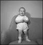 Photograph: [Baby standing on a couch with their hands clasped]