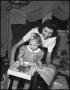 Photograph: [Young girl opening gifts with her mother]