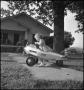 Photograph: [Photograph of a young girl playing in a walking toy plane]