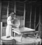 Photograph: [Young woman pouring grain into a mill]