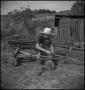Photograph: [Boy fixing farm equipment]