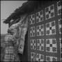 Photograph: [Man and woman hanging quilts outside]