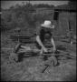 Photograph: [Boy fixing farm equipment, 2]