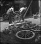 Photograph: [Two men hammering a wheel]