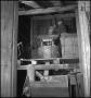Photograph: [Man pouring grain into a mill]