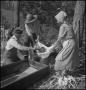 Photograph: [Two women and a man straining sorghum molasses(1)]