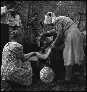 Primary view of object titled '[Man and two women straining sorghum molasses(1)]'.