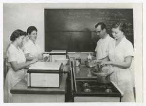 Primary view of object titled '[Four students in classroom cooking]'.
