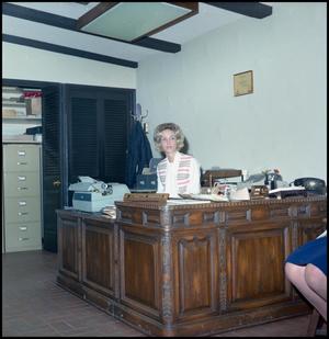 Primary view of object titled '[Woman sits at an office desk]'.
