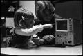 Photograph: [Woman and girl working with a pitch machine]