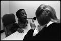 Thumbnail image of item number 1 in: '[Woman using an otoscope to look at boy's throat]'.