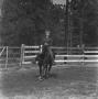 Photograph: [Woman Riding a Horse in a Fenced Area]
