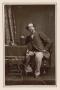 Photograph: [Photograph of Charles Dickens sitting at table with book]