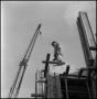 Photograph: [Worker standing on top of building]