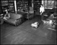 Photograph: [Boy waxing the floor in a library]
