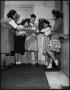 Photograph: [Six young women standing together around telephone]