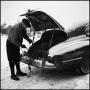 Photograph: [Man untangling rope in the trunk of his car]