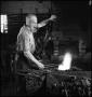 Photograph: [Man heating metal in a forge]